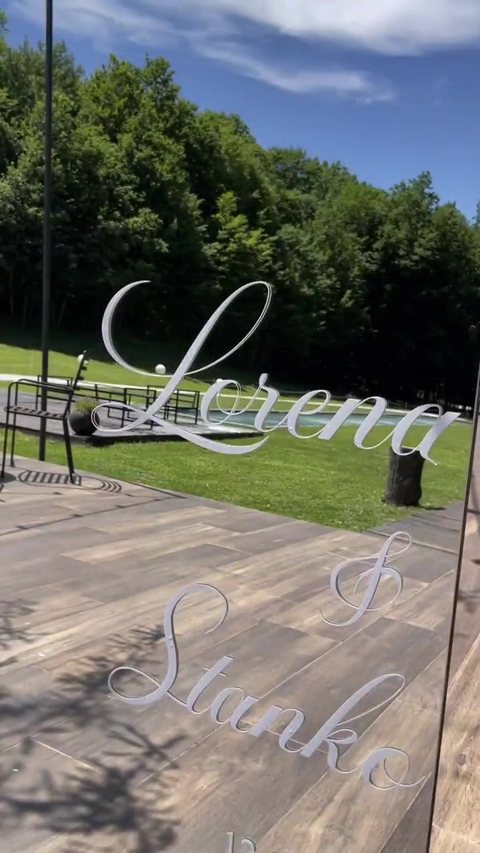 Video: visoko lučno ogledalo s imenima Lorena & Stanko na travnjaku ispred svijetle dvorane.